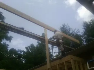Carpenter setting a ridge beam over a new addition frame — Ice Dam Removal by Roofing Brothers in Hilltown
