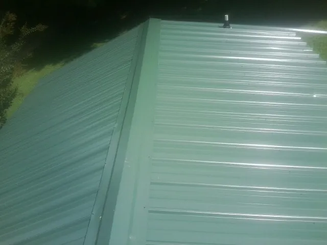 New green metal panels meeting at the ridge of a roof — Flat Roof Repair work by our crew in Hilltown