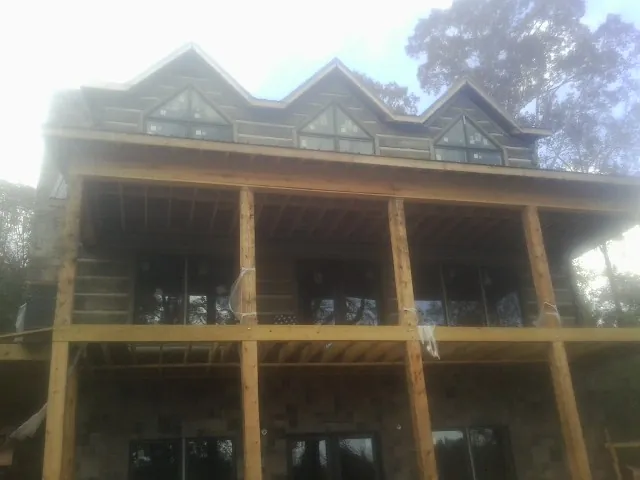 Dormers and porch framing on a large log home under construction — Roof Coating work by our crew in Hilltown