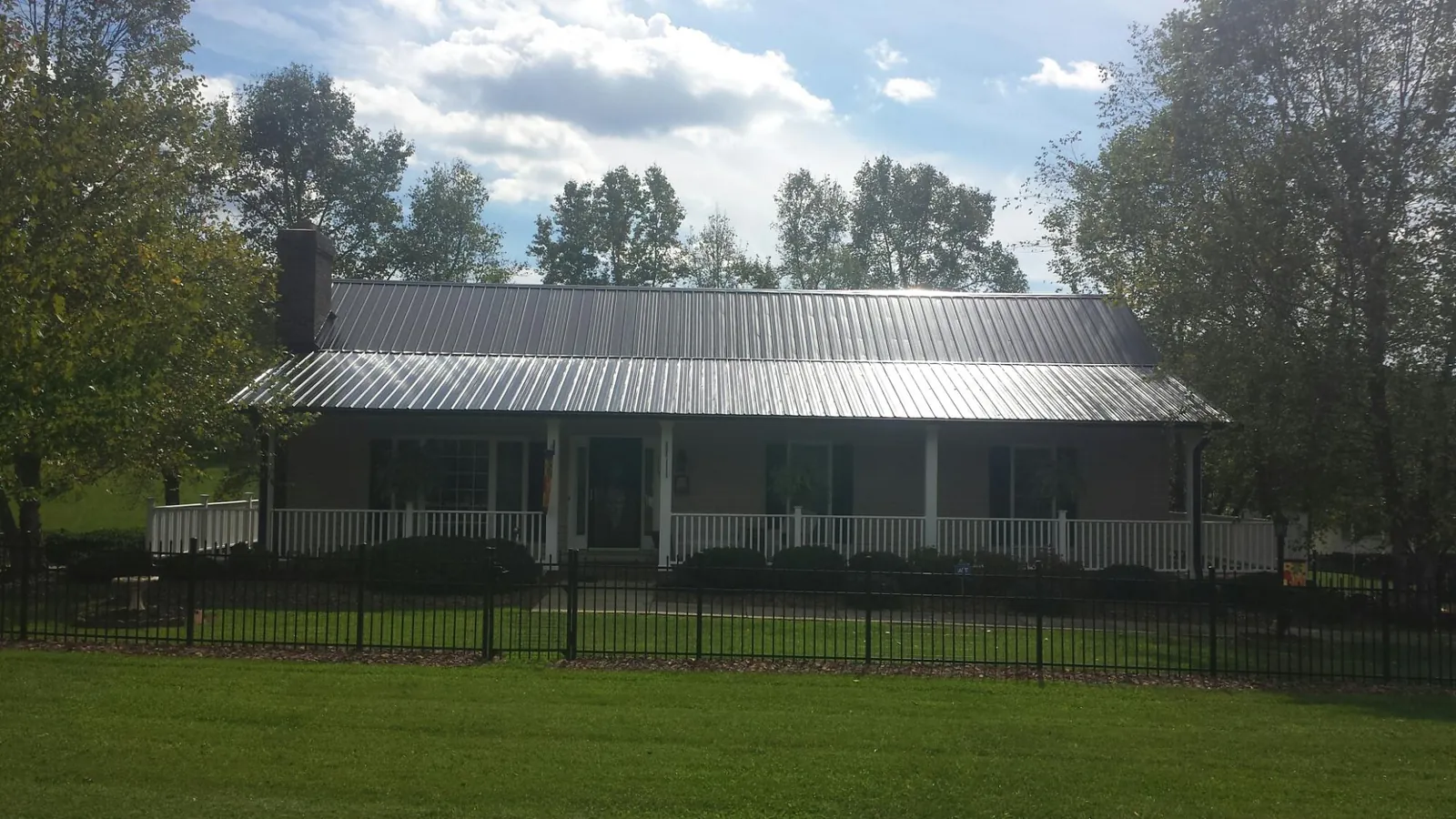Gray metal roof on a brick ranch with a full width front porch — Gutter Guard Installation work by our crew in Hilltown