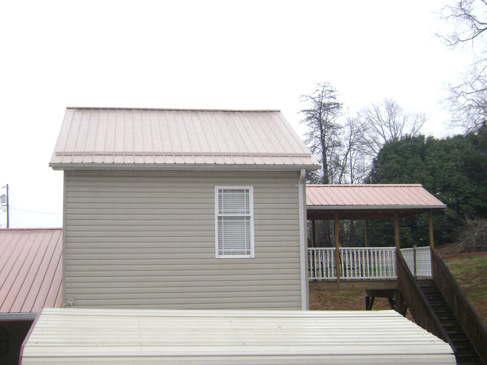 Tan metal roofs on a two story addition and attached porch, from a Roof Replacement job in Hilltown