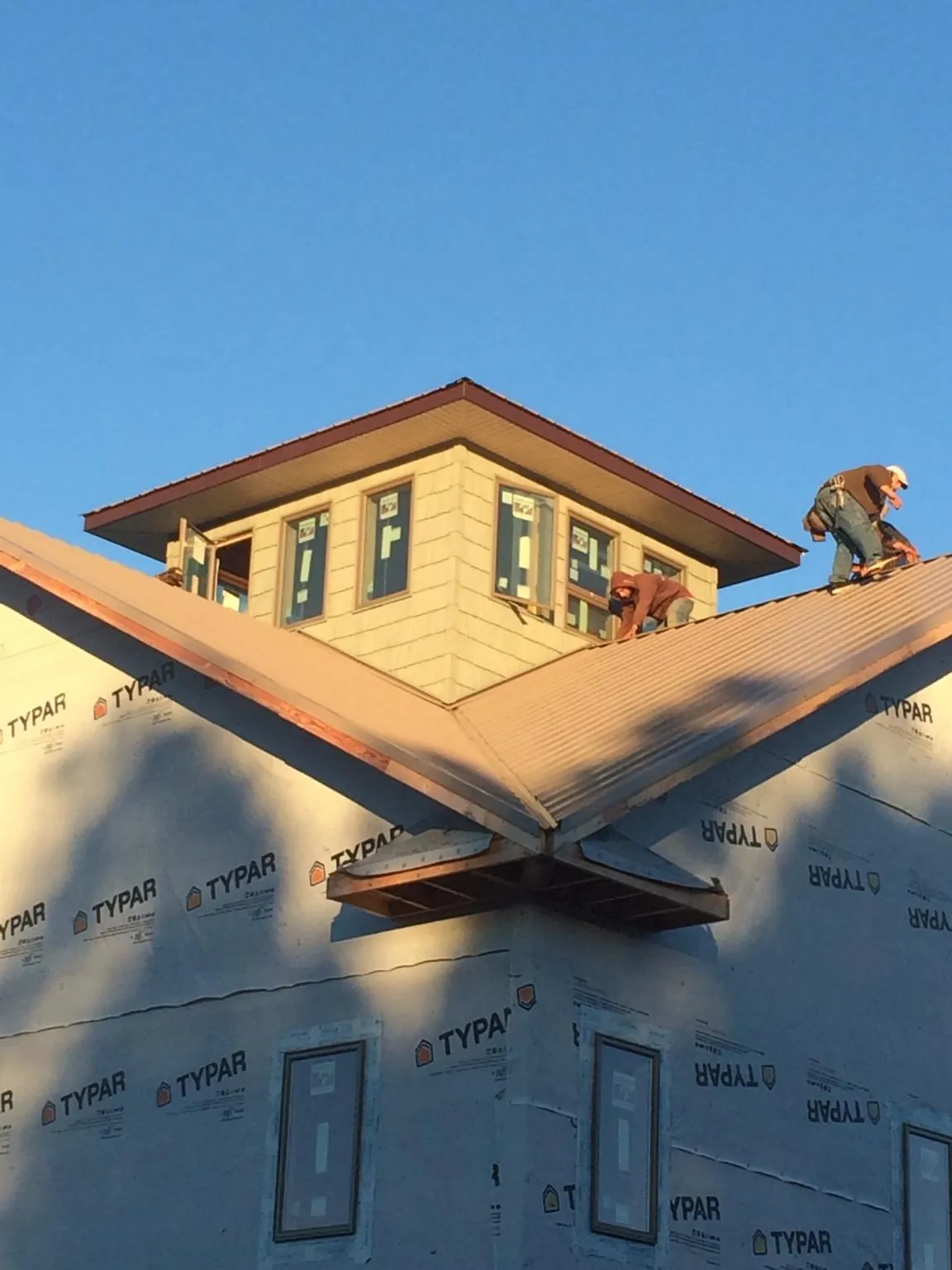 Roofers working around a rooftop cupola on a new metal roof at sunset — Roof Waterproofing in Hilltown by Roofing Brothers